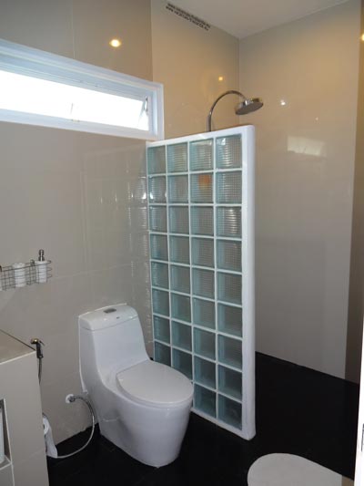 bathroom with a large Italian shower, sink, and toilet right next to the two bedrooms